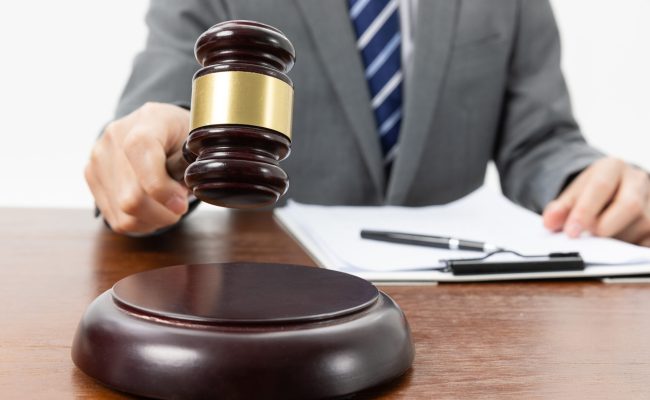Closeup shot of a person with a gavel in hand and papers on the table A closeup shot of a person with a gavel in hand and papers on the table